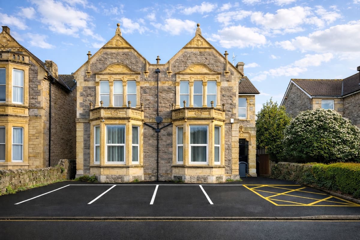 Beaconsfield House in sunshine, showing the carved stone gables, three tiers of bay windows and the level, marked car park directly in front of the building.